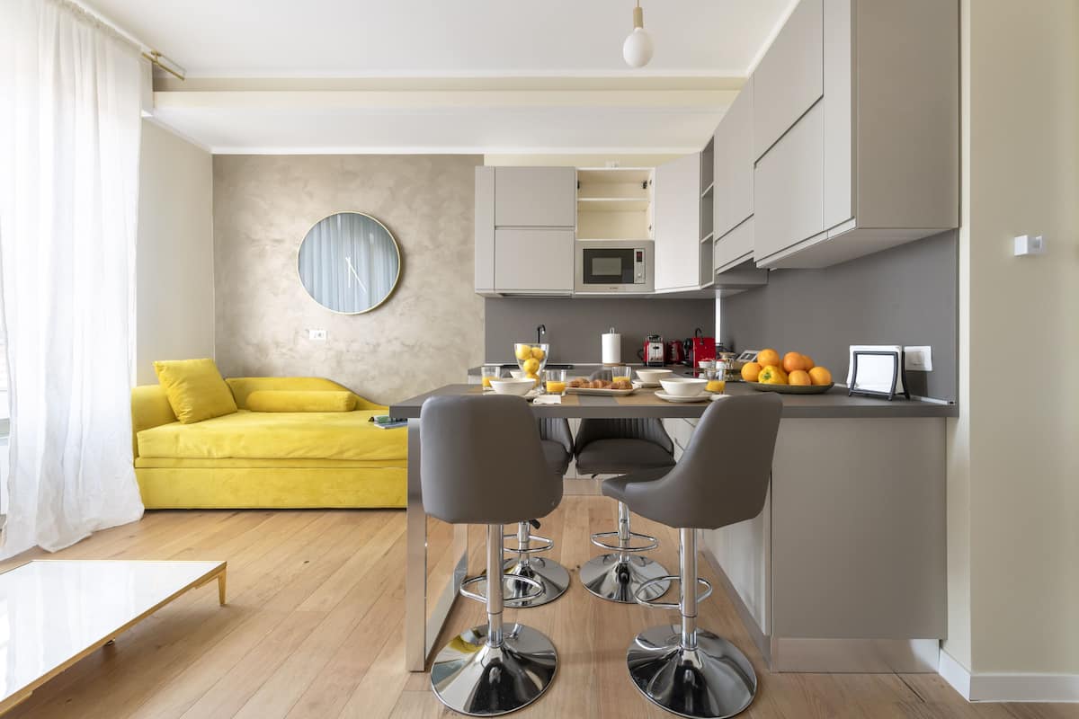 Una cocina moderna con comedor, un sofá amarillo y un espejo redondo en la pared.