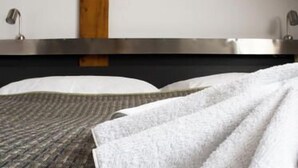 Una habitación de hotel moderna con una cama grande, un panel de madera decorativo y un diseño minimalista.