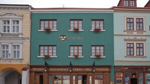 Un edificio con fachada verde, múltiples ventanas y un letrero que dice "PENZIONE RESTAURACE CERNY OREL PIVOVAR".