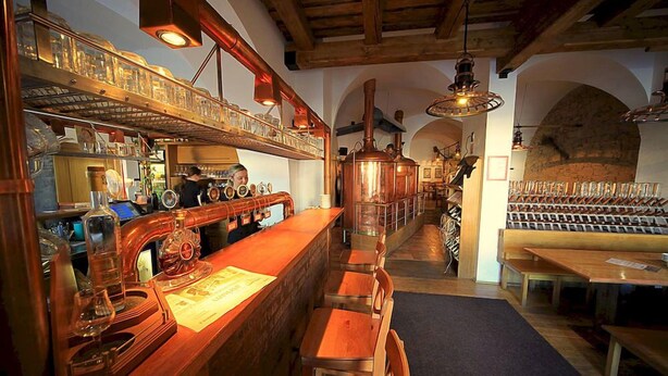 Zona de bar con mobiliario de madera, una barra alargada y una estantería para vinos al fondo.