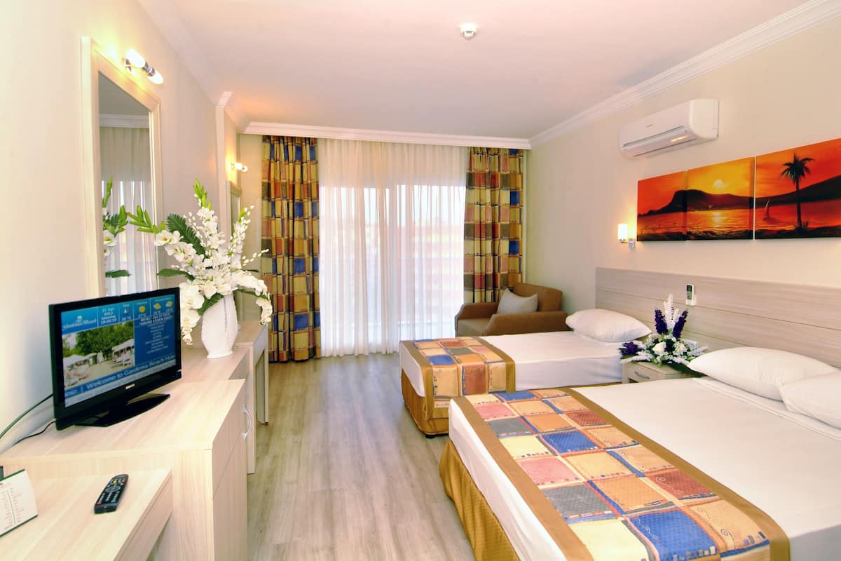 A hotel room with a bed, a desk with a TV, a mirror, and a painting on the wall.