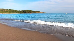 A beach with clear blue water, a sandy shore, and a distant rocky coastline. - Gardenia Beach Hotel - All Inclusive (Alanya)