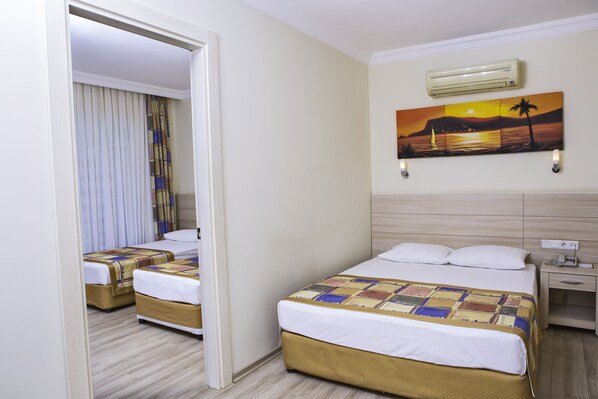 A hotel room with two beds, a nightstand, an air conditioner, and a painting of a sunset. - Gardenia Beach Hotel - All Inclusive (Alanya)