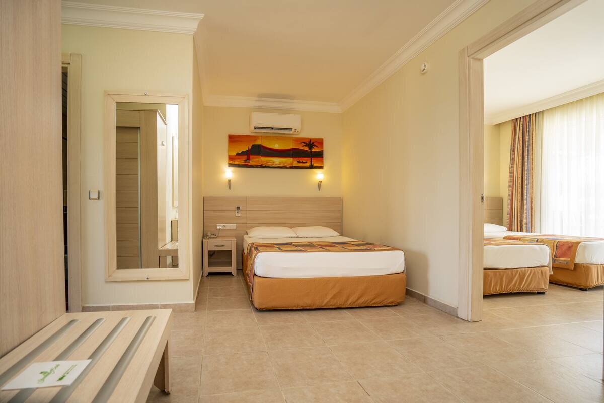 A hotel room with a bed, a bedside table, a mirror, and a painting on the wall.