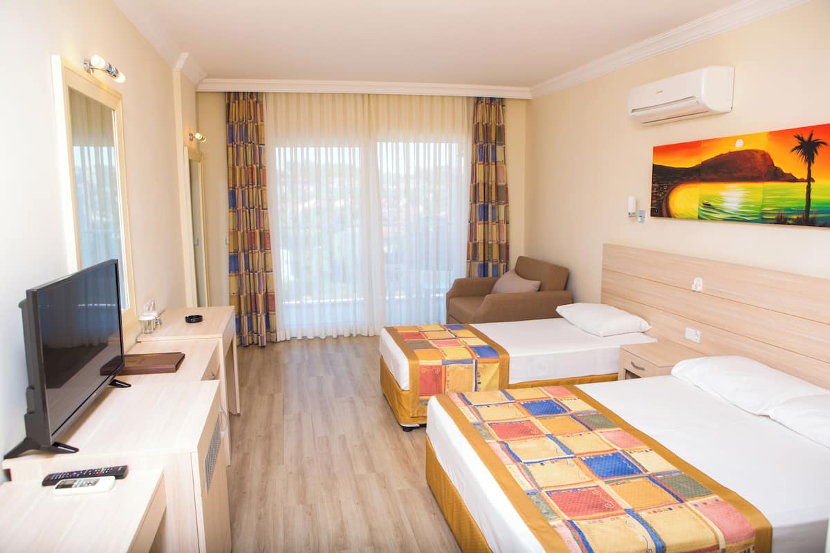 A hotel room with two beds, a TV, a desk, and a painting on the wall.