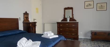Una habitación de hotel con una cama grande, un aparador de madera, un espejo y dos cuadros en la pared.
