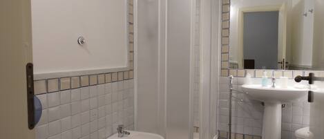 Une salle de bain équipée d’une douche, de toilettes, d’un bidet et d’un lavabo.