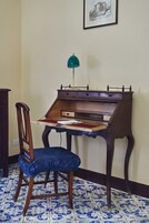 Un escritorio de madera con una silla, una lámpara de escritorio y un cuadro en la pared.