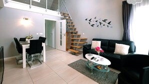 A modern living room with a staircase, a dining area, and a black leather sofa. - My-Cocoon (Court-Saint-Etienne)