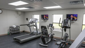 Ein Fitnessstudio mit Laufbändern, Crosstrainern und einem Gewichtsturm.