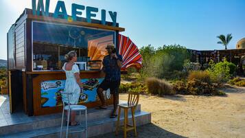 A waffle stand with a clear sign, a counter, and a seating area with a chair and a stool.