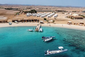 A coastal resort with multiple white-roofed villas, a sandy beach, and clear turquoise waters. - Marsa Nakari Village (Marsa Alam)
