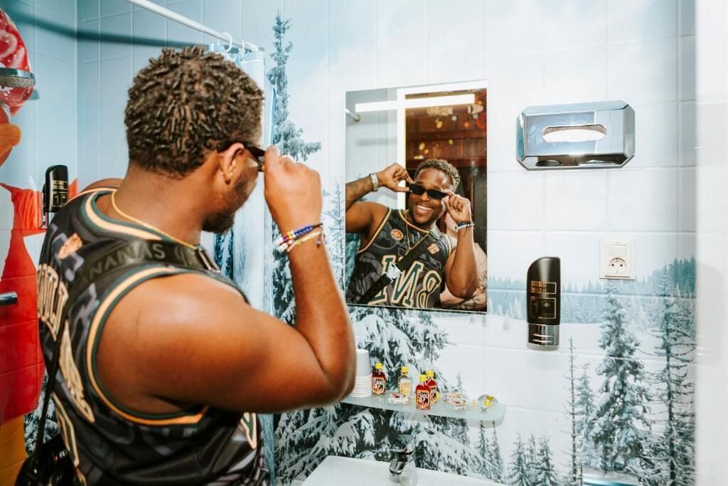 Un baño con espejo, lavabo y estante con artículos de aseo.