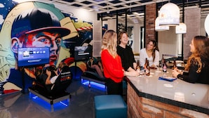 A bar area with a counter, seating, and a mural on the wall. - Amsterdam Teleport Hotel (Amsterdam)