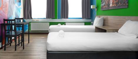 A room with two beds, a table with chairs, a radiator, and a large painting on the wall.