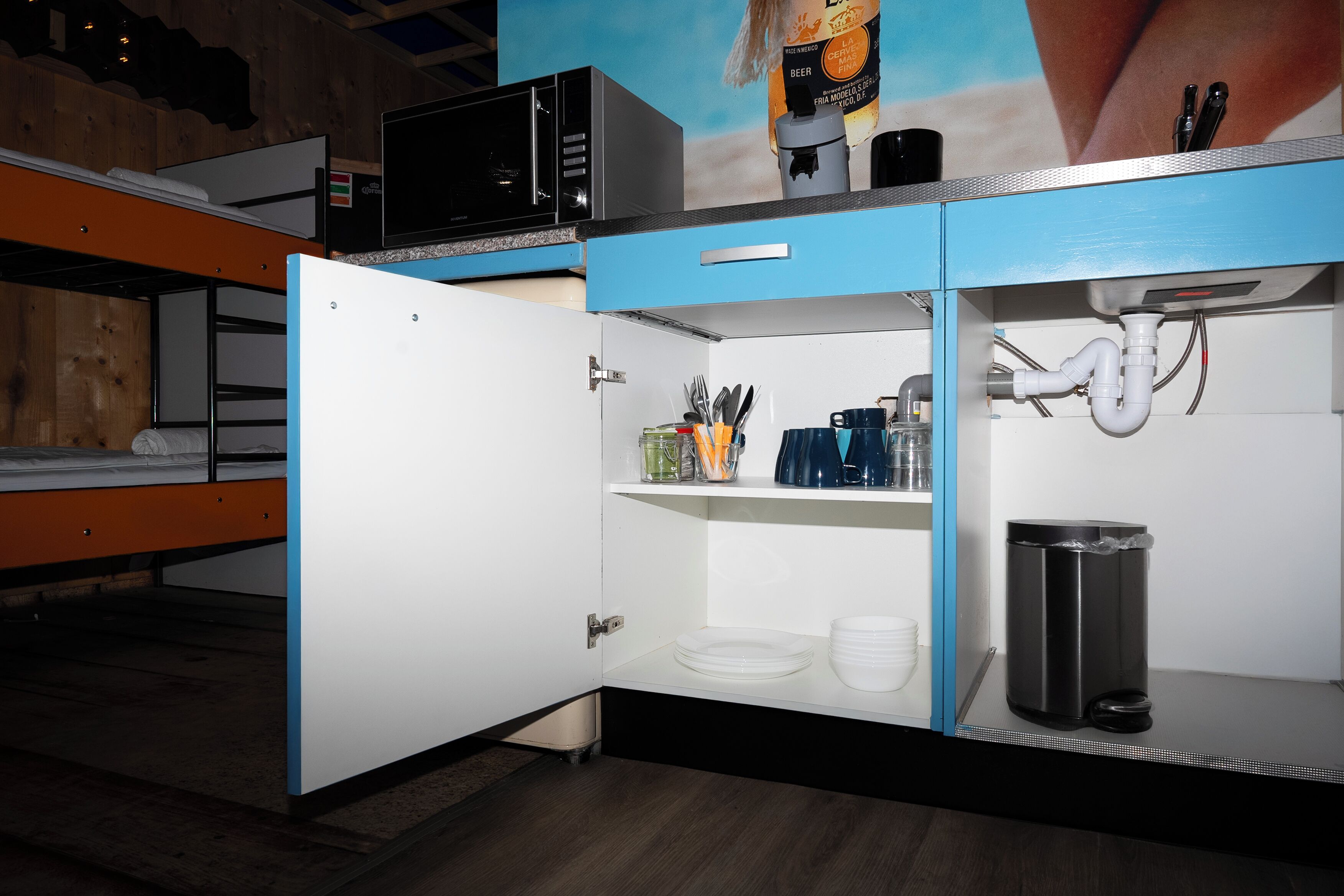 A compact kitchenette with a microwave, coffee maker, and a trash bin.