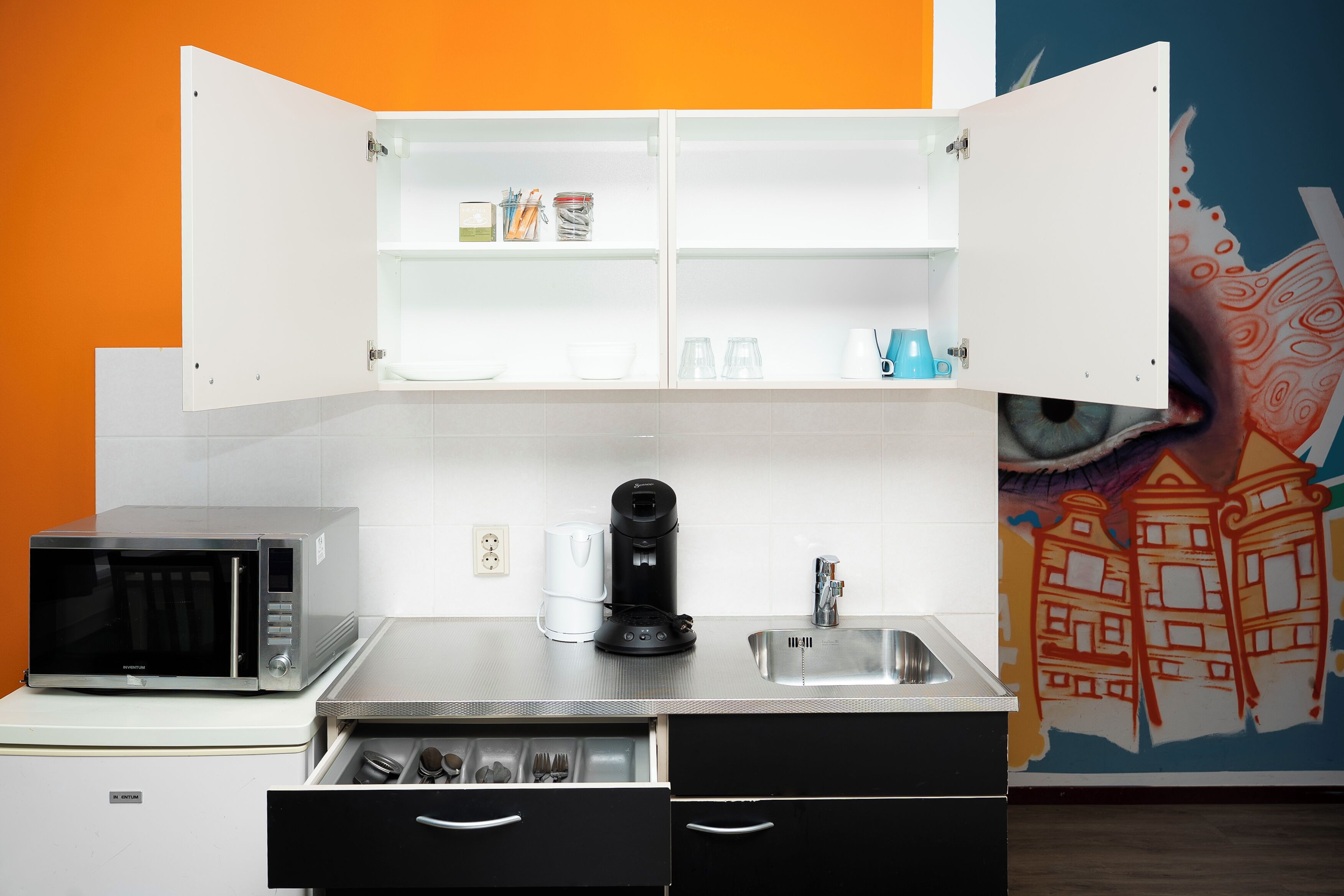 A compact kitchen with a microwave, coffee maker, and a sink.