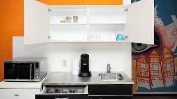 A compact kitchen with a microwave, coffee maker, and a sink.