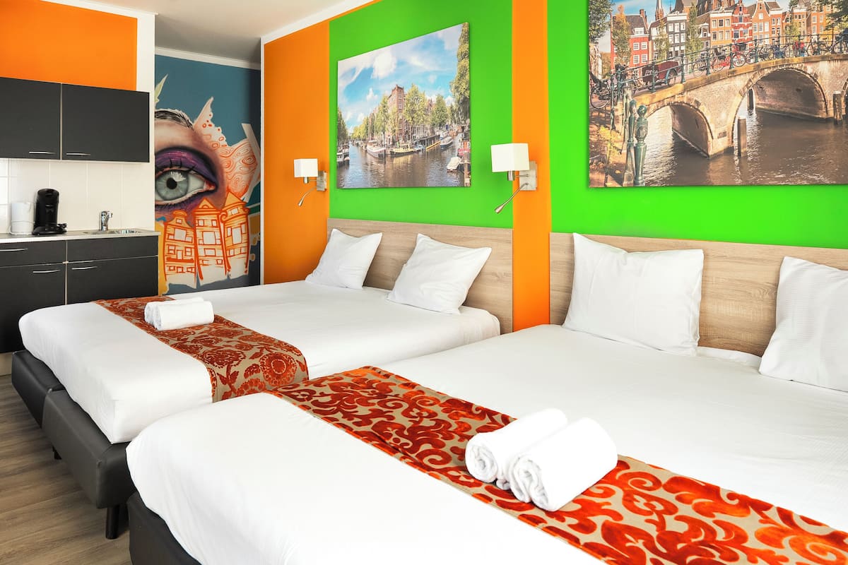 A hotel room with two beds, orange and green walls, and a mural of a cityscape.