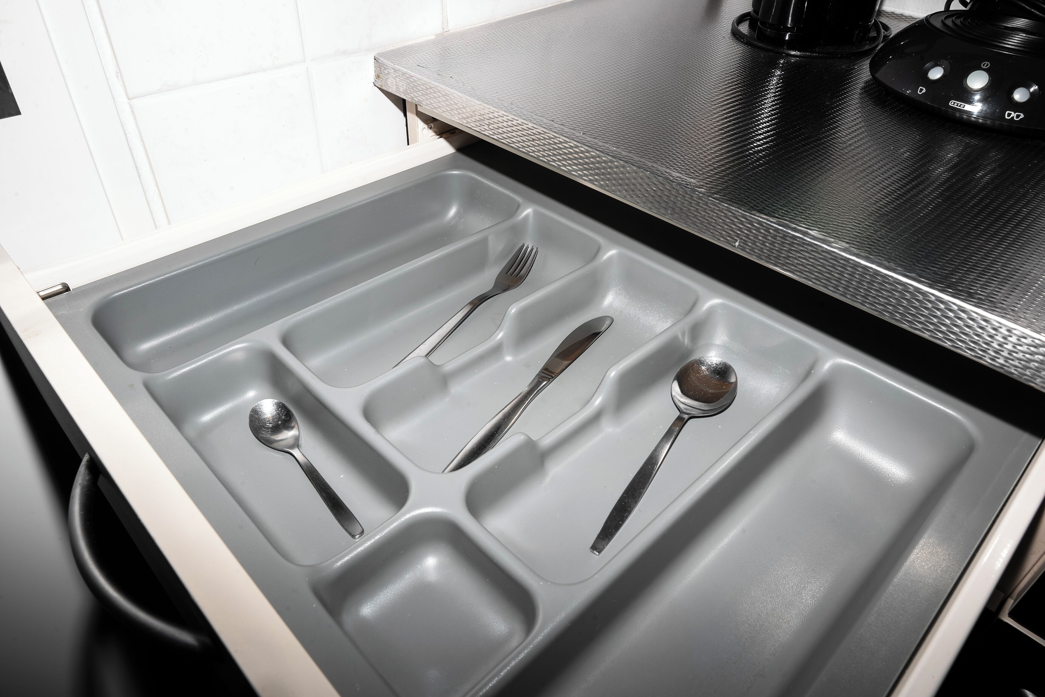 Un cajón de cocina con utensilios.