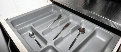 Un cajón de cocina con utensilios.