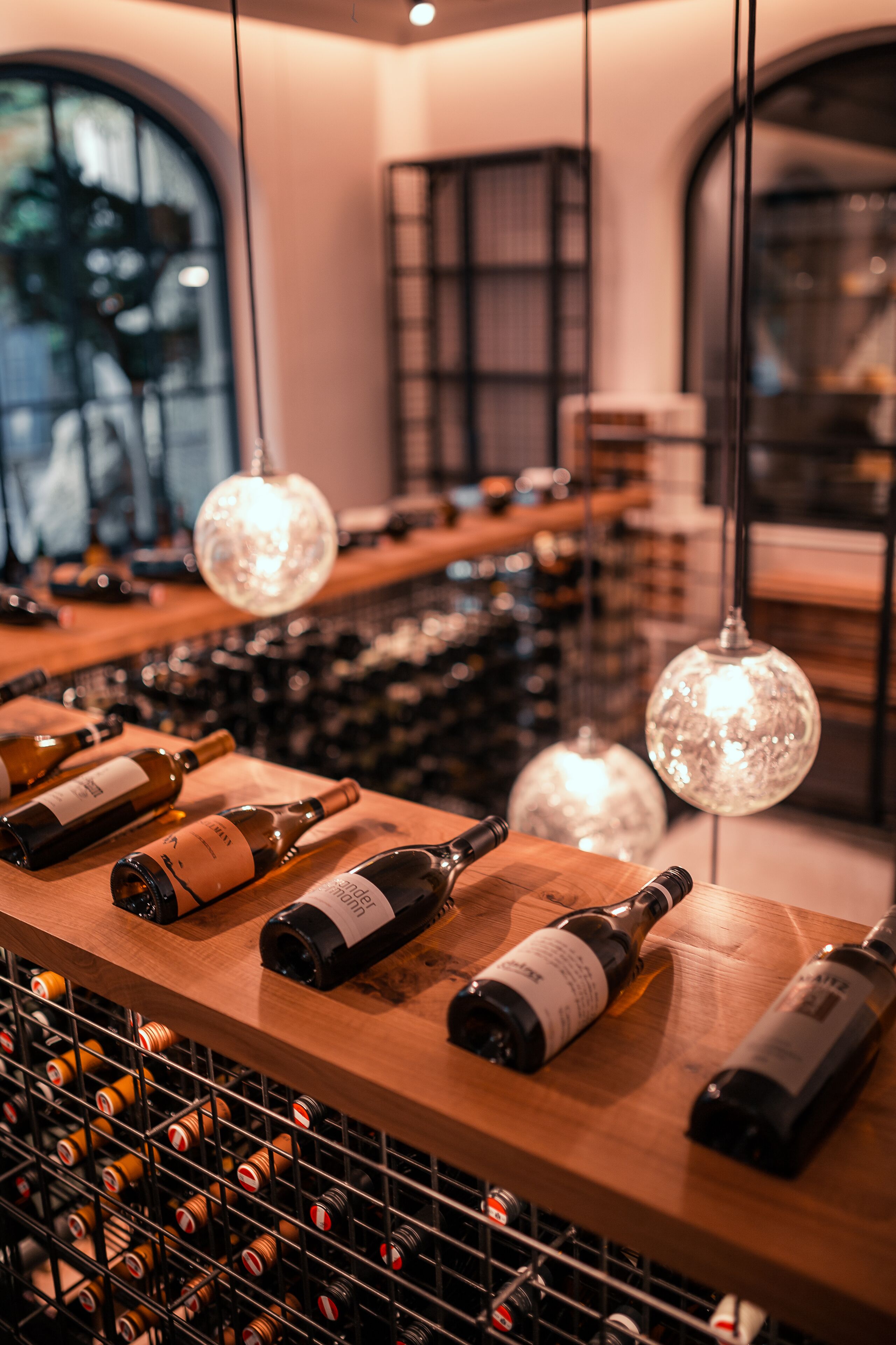 A wine cellar with bottles on shelves and hanging from the ceiling.