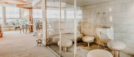 A modern spa with a glass wall, a seating area with a sofa and chairs, and a stone floor.