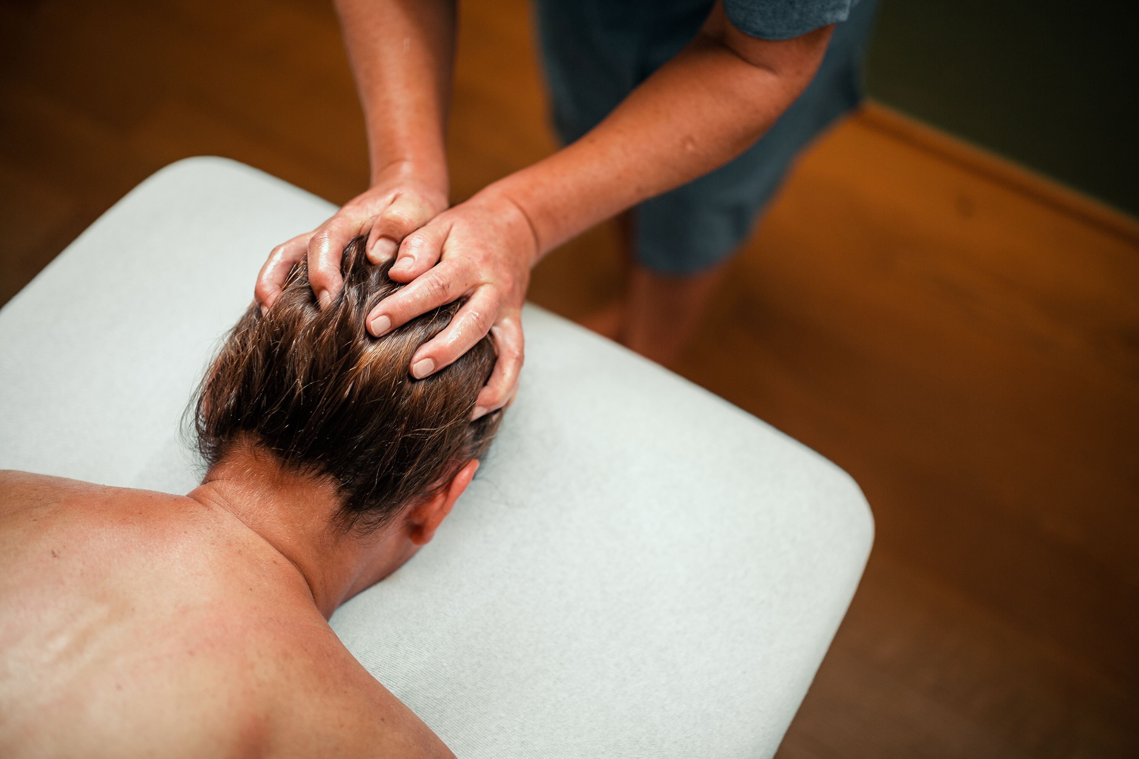 A person receiving a head massage on a massage table.