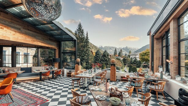 A dining area with checkered flooring, wooden furniture, and large windows offering mountain views. - Sendlhofer's (Bad Hofgastein)