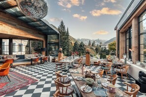 A dining area with checkered flooring, wooden furniture, and large windows offering mountain views. - Sendlhofer's (Bad Hofgastein)