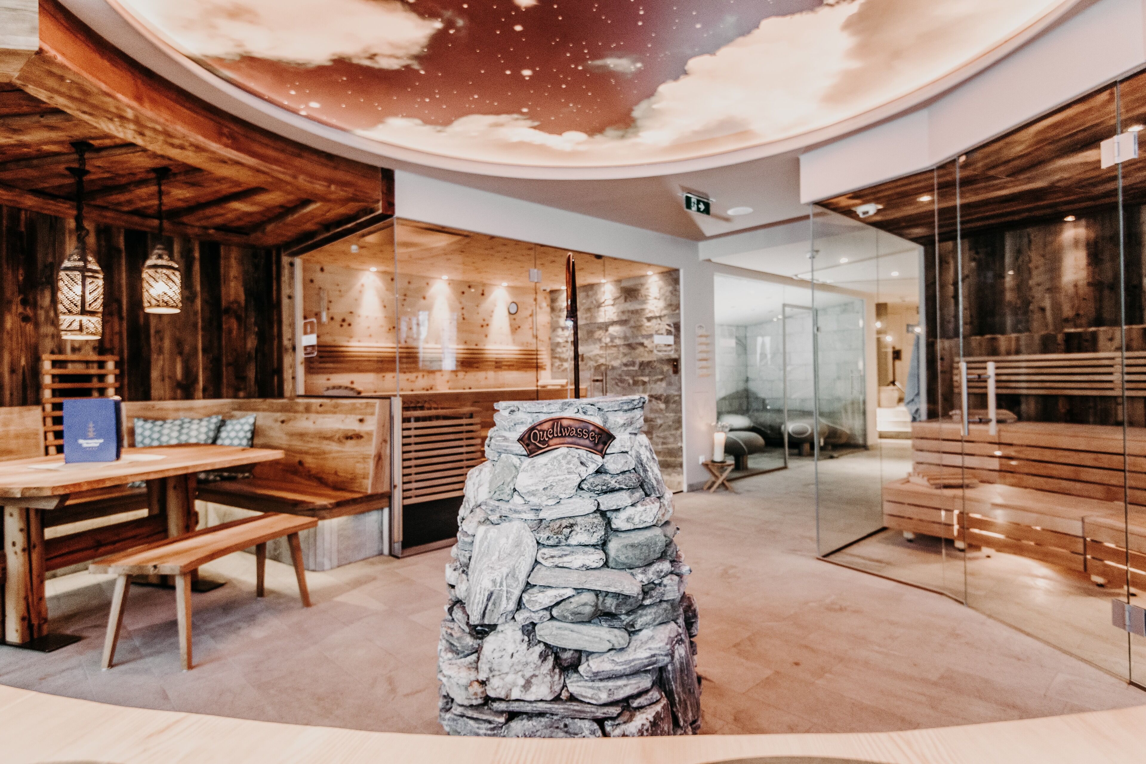 A restaurant with wooden interiors, a stone centerpiece, and a ceiling with a starry design.