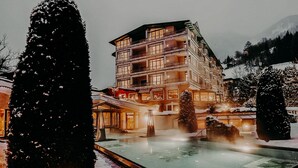 A multi-story hotel with balconies, a pool area, and snow-covered surroundings. - Sendlhofer's (Bad Hofgastein)
