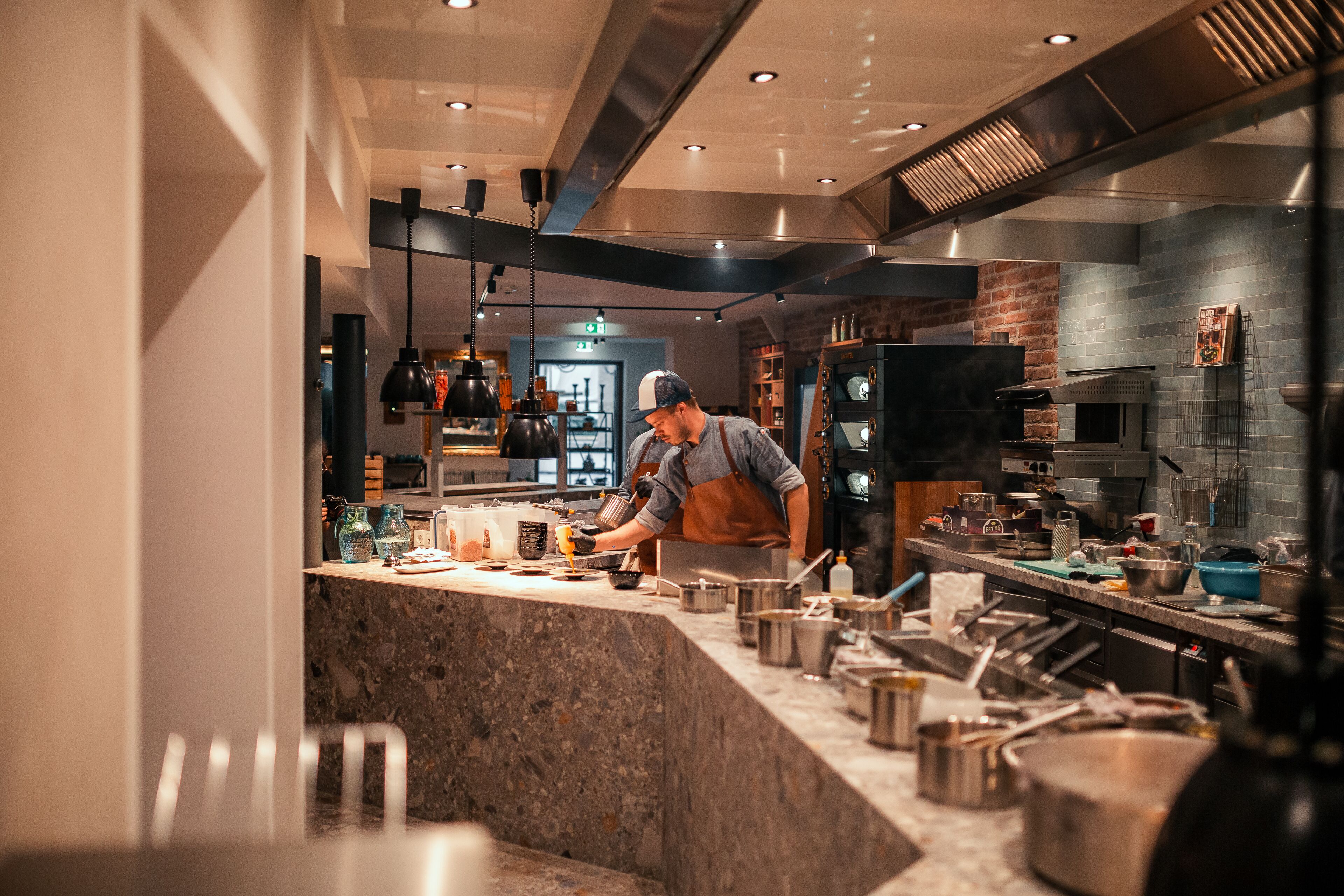 Une cuisine moderne avec un plan de travail en marbre, des appareils électroménagers en acier inoxydable et un mur en briques.
