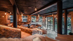 A spacious lobby with a high ceiling, exposed beams, and large windows offering views of the outdoors. - Sendlhofer's (Bad Hofgastein)