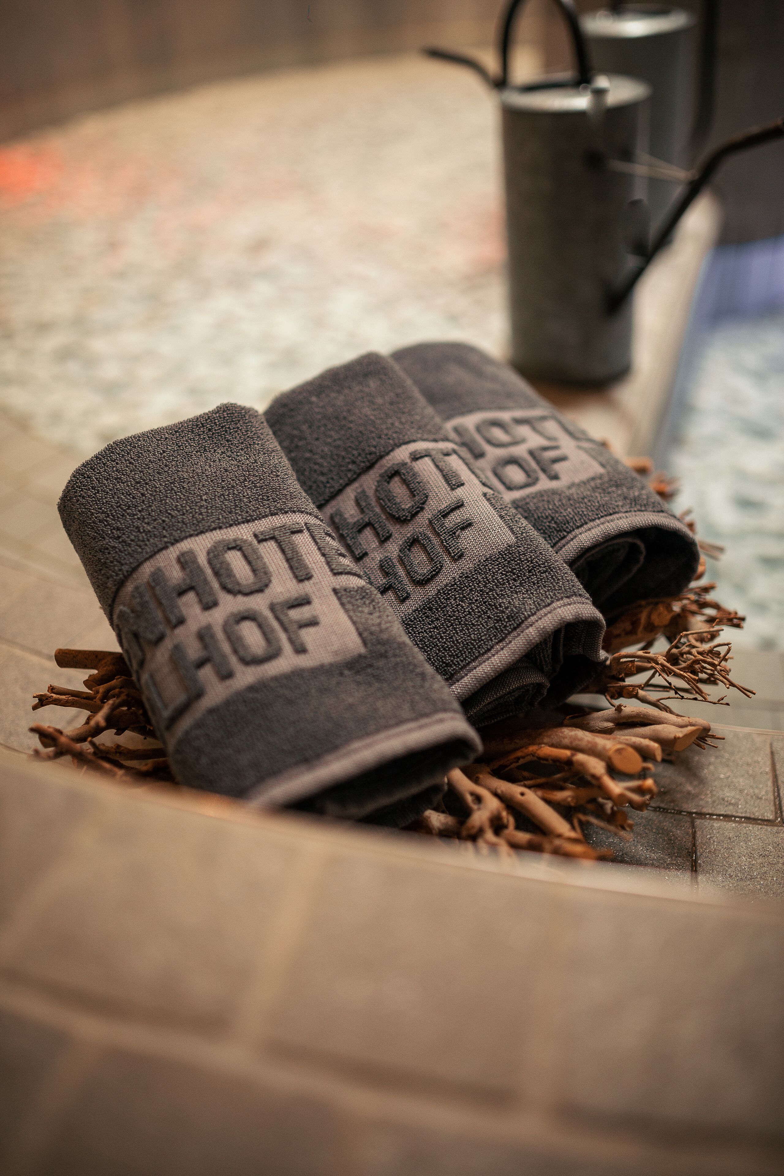 Ein Handtuch mit dem Aufdruck "HOTEL OF", ein Metallbehälter und eine Holzoberfläche.