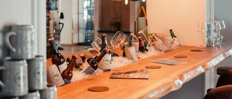 A bar area with a wooden counter, hanging light bulbs, and various bottles and glasses.
