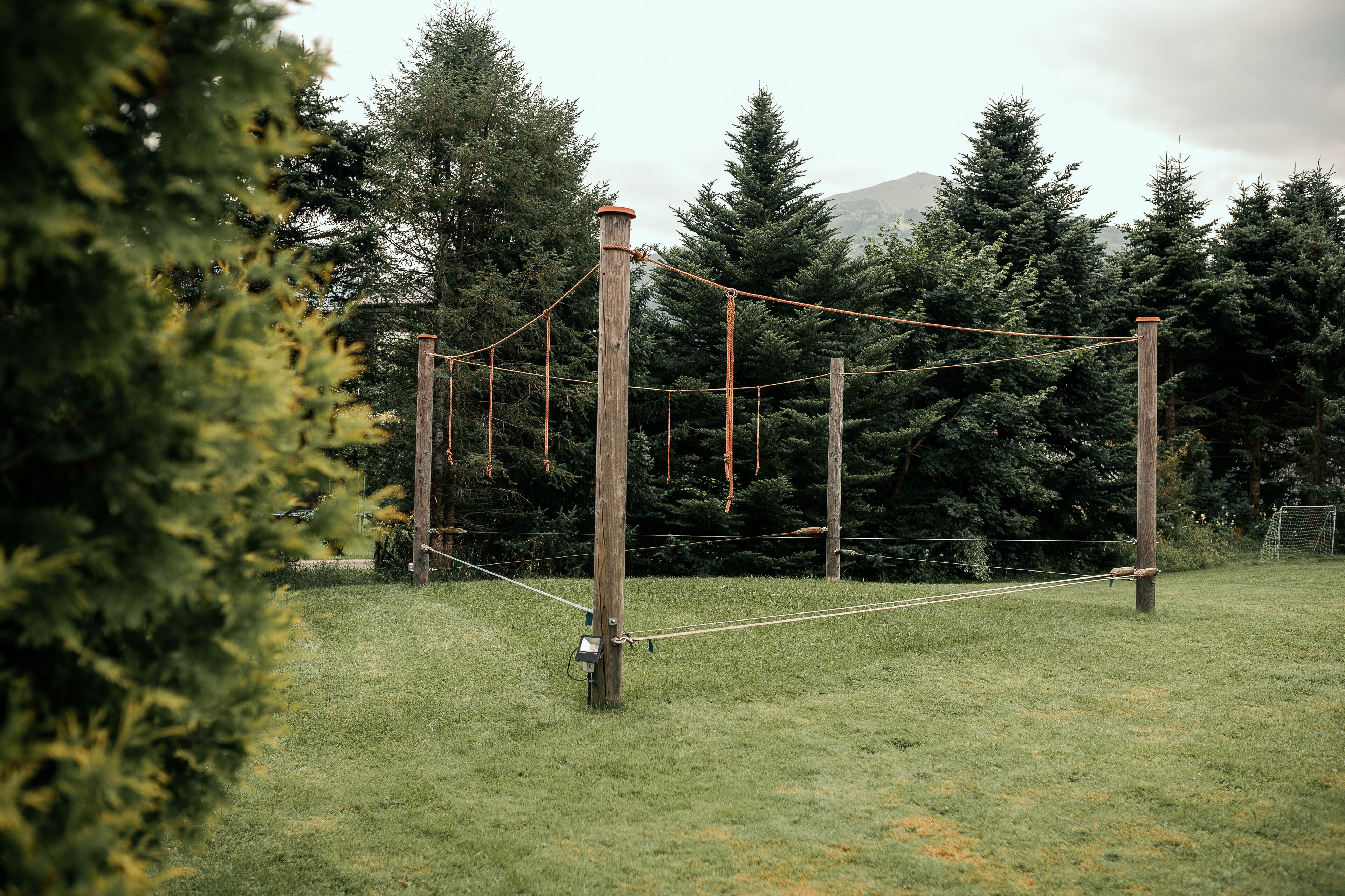Un puente colgante en un campo cubierto de hierba con árboles al fondo.