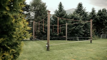 Un puente colgante en un campo cubierto de hierba con árboles al fondo.