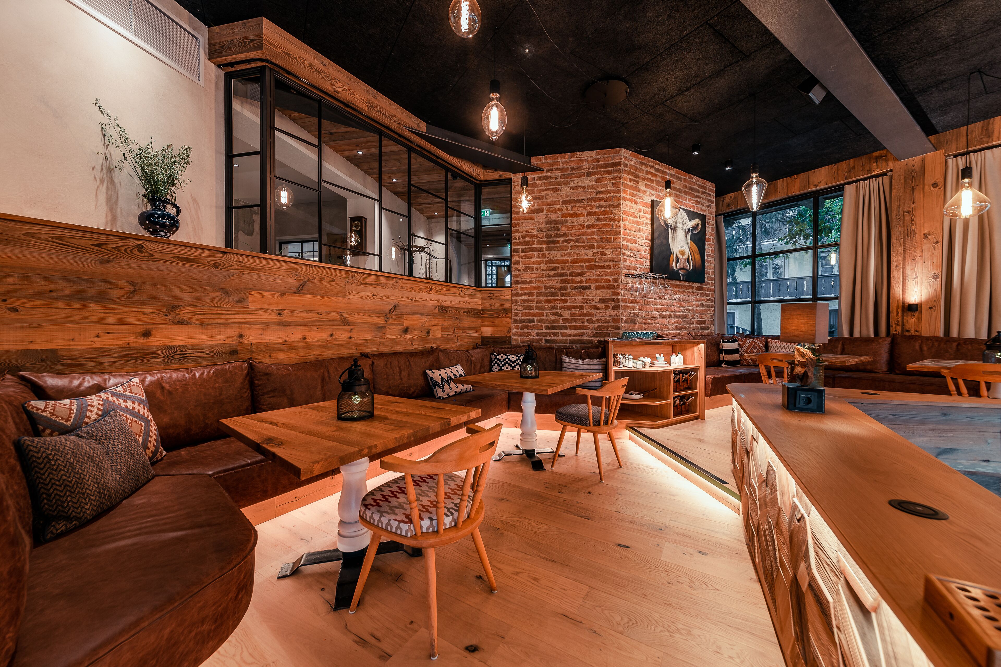 Un restaurante acogedor con muebles de madera, paredes de ladrillo y grandes ventanales.