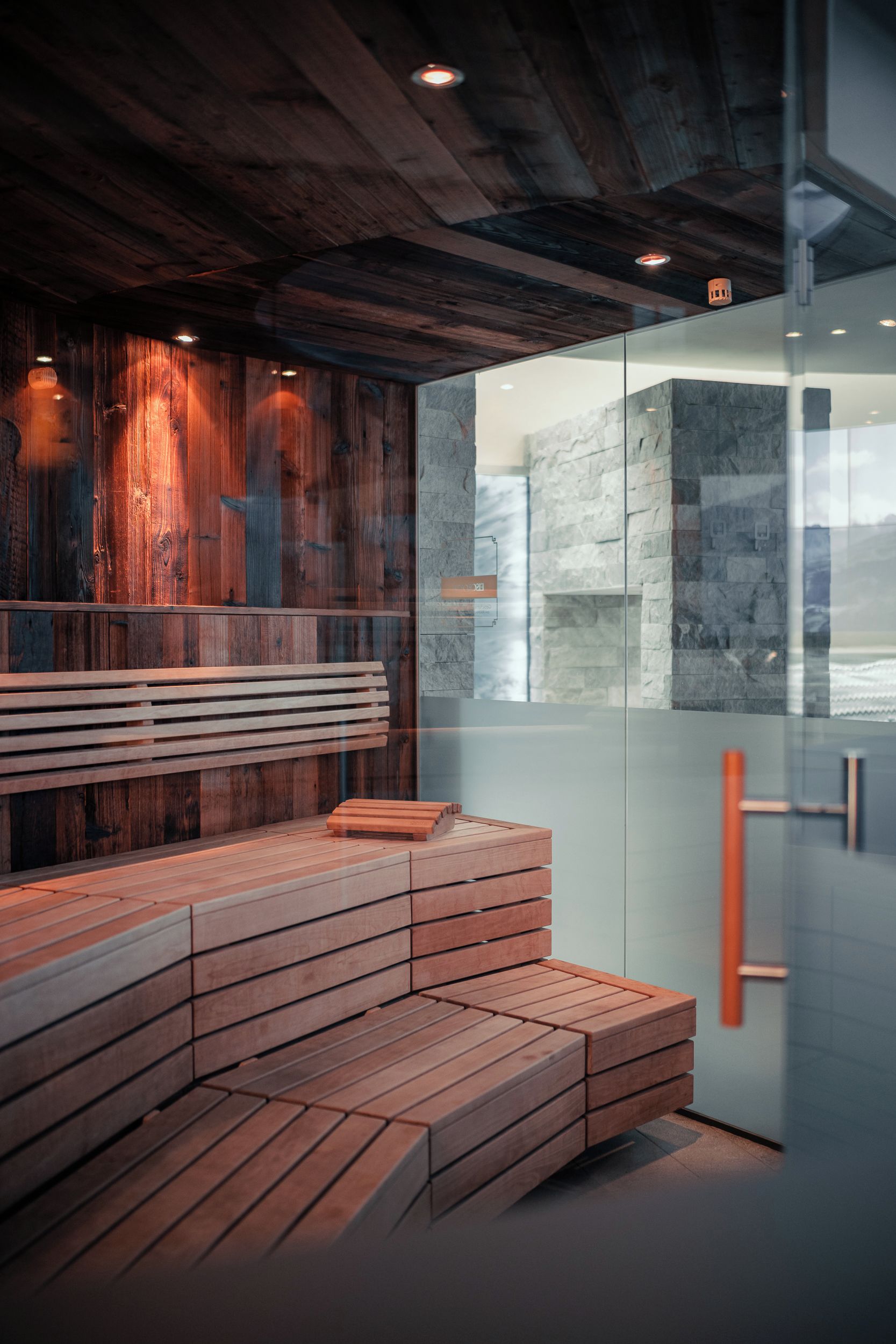 A modern interior with a wooden bench and a glass partition.