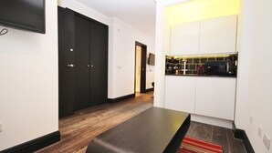 A modern kitchen with white cabinets, a black countertop, and a built-in oven. - 6 Portobello Road (London)