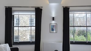 A modern hotel room with a bed, a sofa, a table, and two windows with curtains. - 6 Portobello Road (London)