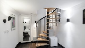 A modern interior with a spiral staircase, white walls, and a dark wooden floor. - 6 Portobello Road (London)