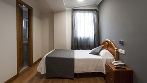 Ein Schlafzimmer mit einem Bett, einem Nachttisch und einem Fenster mit Vorhängen.