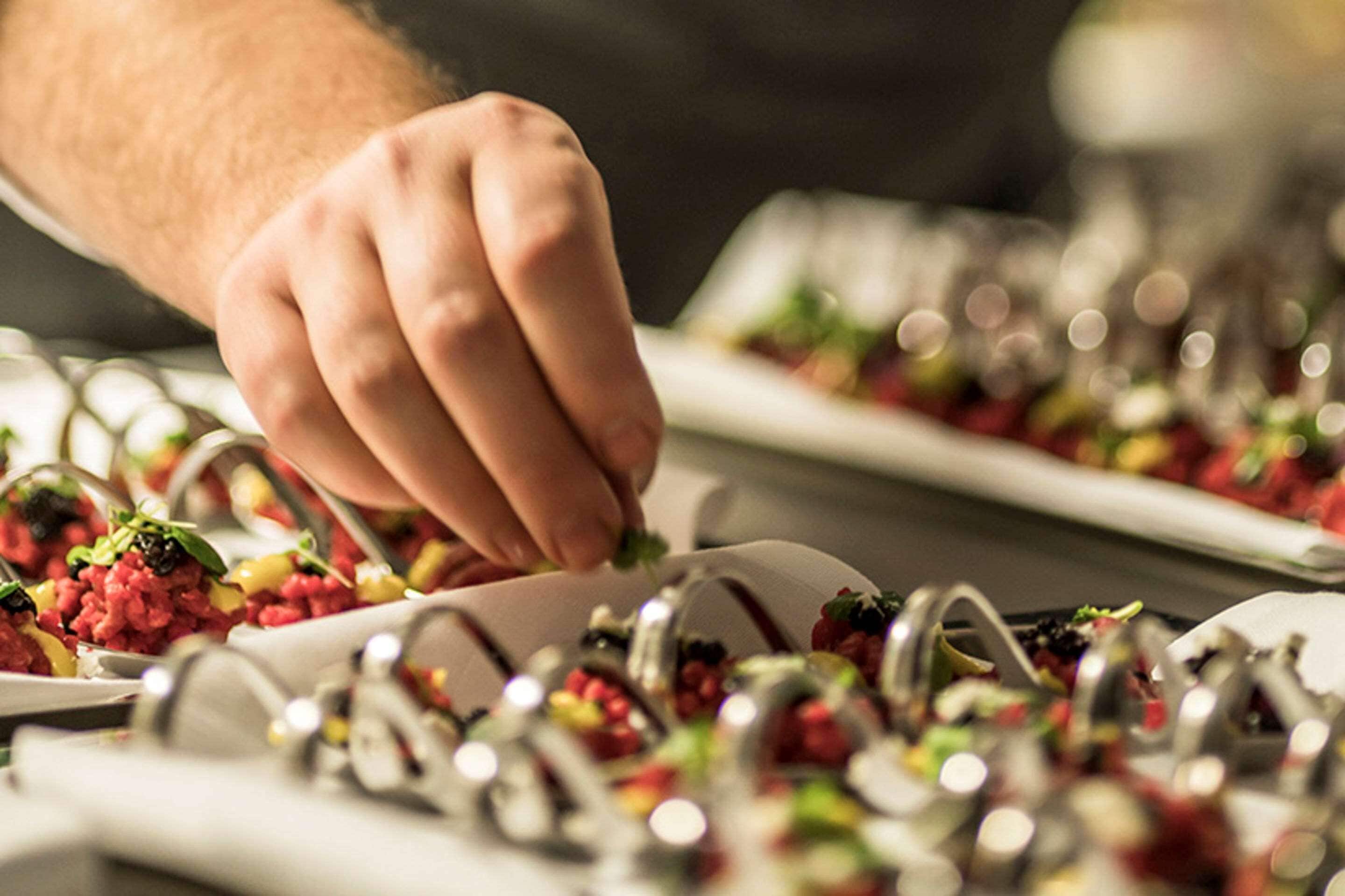 A hand placing a food item on a plate.
