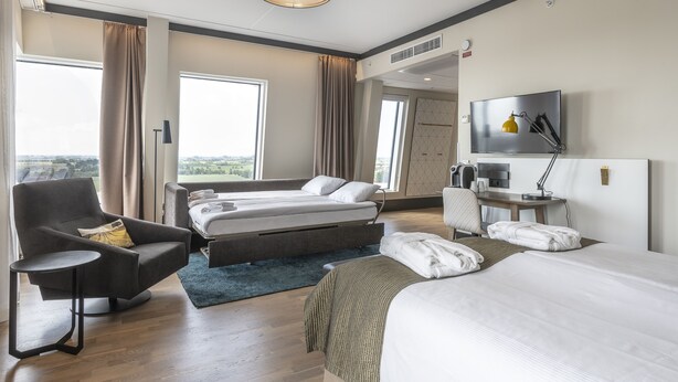 A modern hotel room with a bed, a sofa, a desk, and a TV. - Quality Hotel View (Malmö)