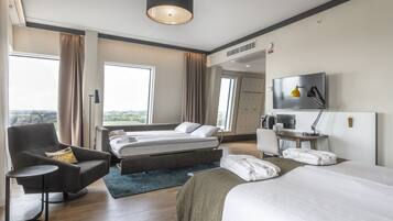 Een moderne hotelkamer met een bed, een sofa, een bureau en een televisie.