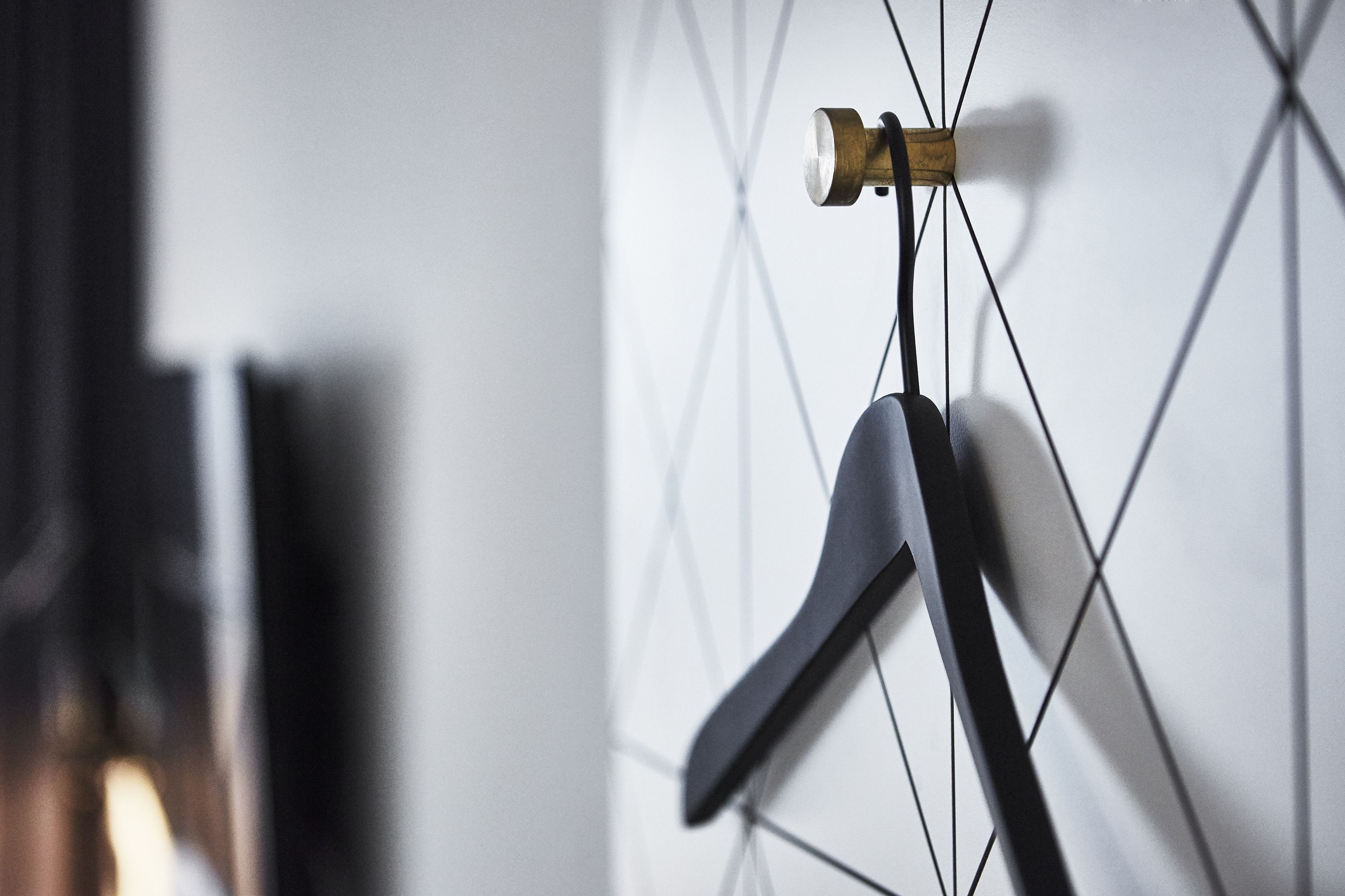 A modern interior with a geometric wall design and a hanging coat rack.