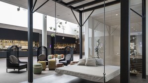 Un espace de détente moderne avec un lit suspendu, des sièges confortables et un bar en arrière-plan.