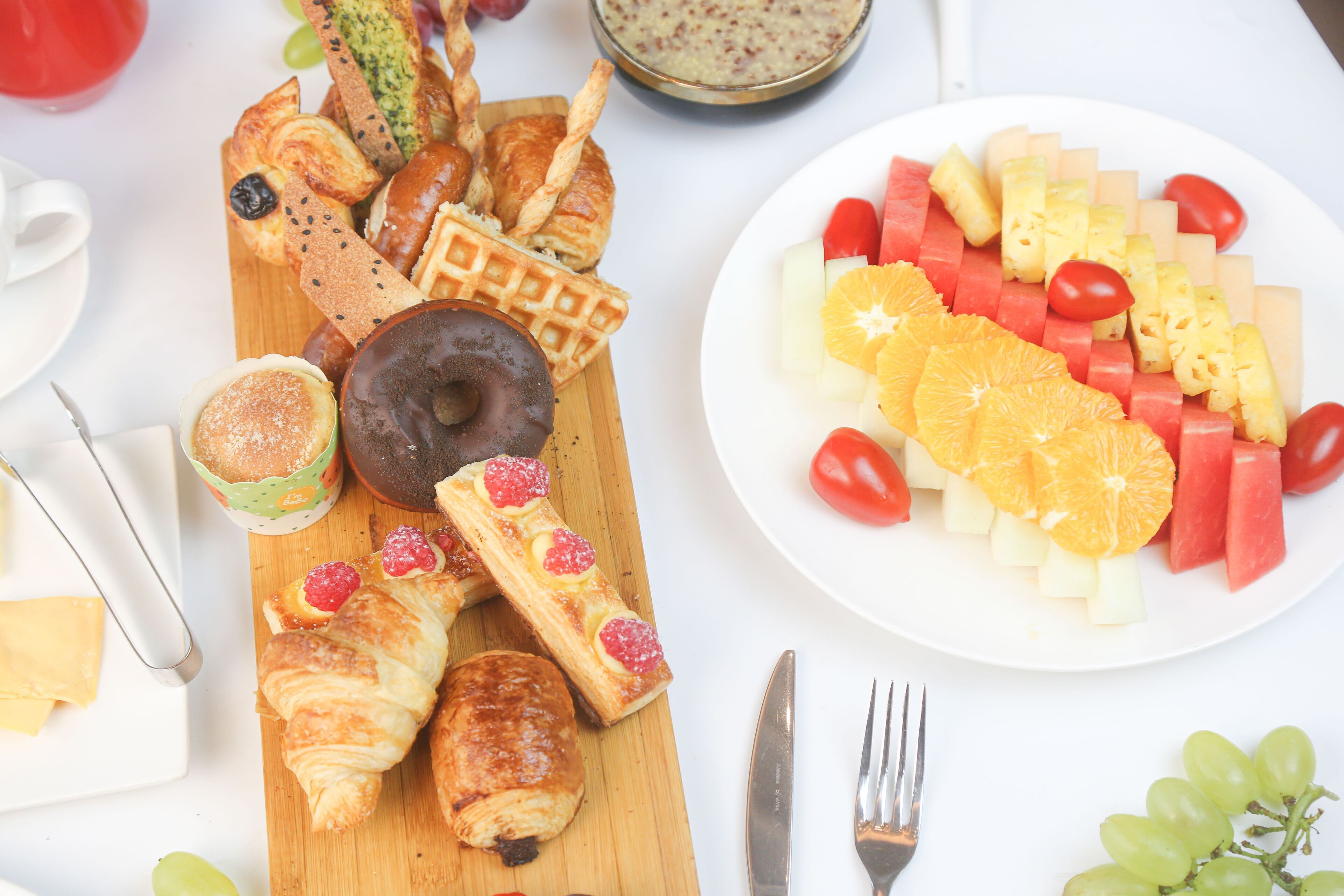 Un assortiment de viennoiseries, de gaufres et une assiette de fruits pour le petit-déjeuner.